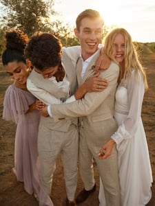 Two groomsmen and and two bridesmaids who are wearing a boho look. They are happy and smiling.