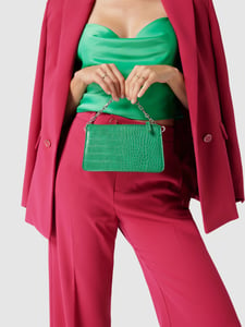 Vrouw in roze broekpak met groene top en handtas