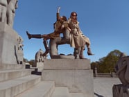 Twee vrouwen in een trenchcoat op een standbeeld