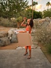 Frau in einem orangenen Kleid isst Pizza
