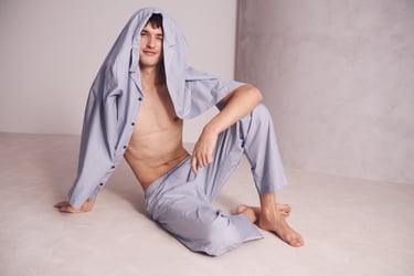 Man zittend op de grond en draagt een lichtgrijze pyjama