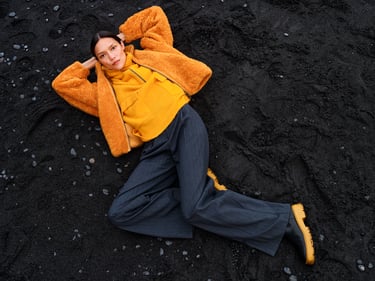 Vrouw ligt op een zwarte ondergrond en draagt een oranje vest