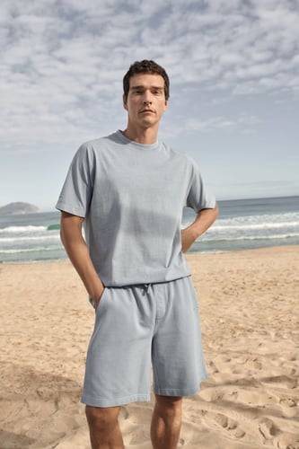 Mann mit Shirt und kurzer Hose am Strand