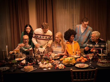 A group of friends which is eating christmas dinner at a table and enjoying their time together.