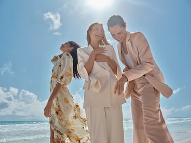 Weddingguests in suits and floral dress at the beach