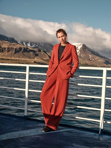 Vrouw staat op een boot en draagt een rood pak