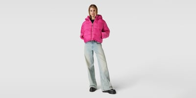 Frau in pinker Pufferjacke und hellblauer Jeans mit Boots