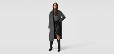 Frau mit kurzem Lederrock in Kombination mit Pullover und Mantel