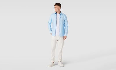 Ein offen getragenes blaues Hemd wird kombiniert mit einer cremefarbenen Hose und Sneaker