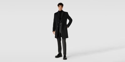 Mann in dunklem Anzug mit Rollkragenpullover und Mantel 