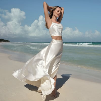 Die Braut, die am Strand mit ihrem Kleid steht 
