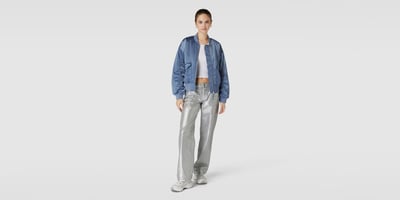 Frau in blauer Bomberjacke und silber Metallic Jeans
