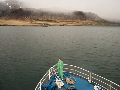 Vrouw staat op een boot in een groen pak