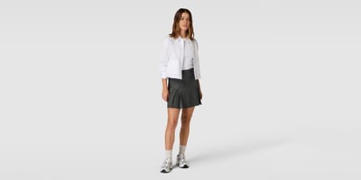 Frau in Hemd, Faltenrock und Tennis Sneakern