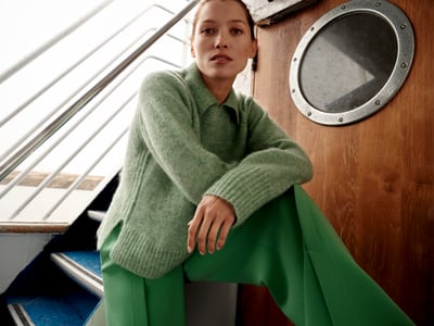 Vrouw staat op een boot en draagt een groene trui