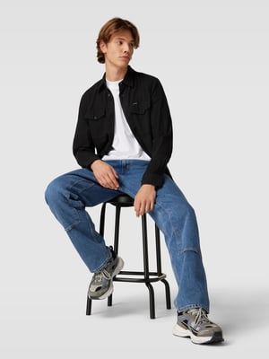 Schwarzes Hemd zu Jeans und Sneakern kombiniert